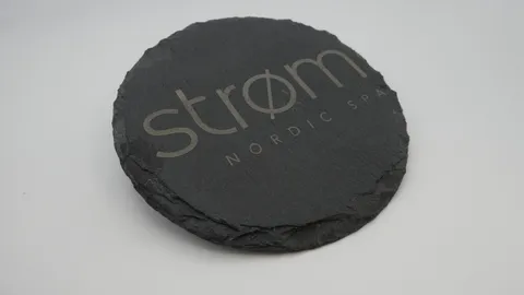Laser etched slate stone coaster featuring precision Strom Nordic Spa minimalist logo design.