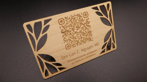 CO2 laser engraving an intricate wooden business card with a custom QR code on a honeycomb workbench.