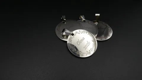 Laser engraved custom name pendants in stainless steel with intricate floral borders and clean script typography.