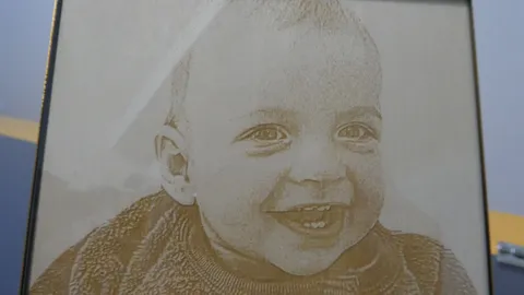Close up of custom laser engraved wood portrait showing high precision halftone detailing on an infant face.