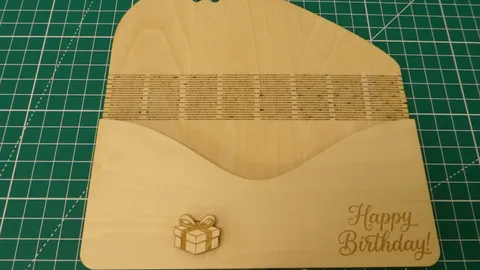 CO2 laser cutting machine scoring a flexible living hinge into a custom wooden birthday gift card envelope.