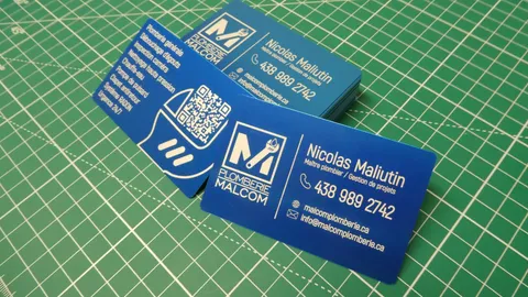 Laser engraved blue aluminum business cards displaying custom plumbing logo and crisp typography.