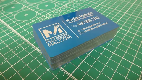 Anodized blue metal business cards showing pristine silver laser engraved text and metallic edges.