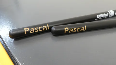 Laser engraved custom wood drumsticks with the name Pascal precisely etched into a black factory finish.