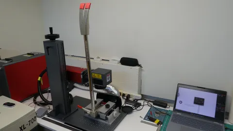 Industrial fiber laser marking station with a steel tool clamped vertically.