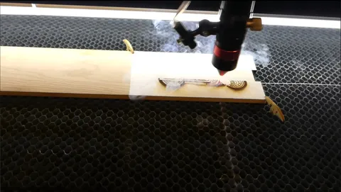 CO2 laser machine cutting custom wooden motorcycle display with precision vector engraving on a honeycomb bed.